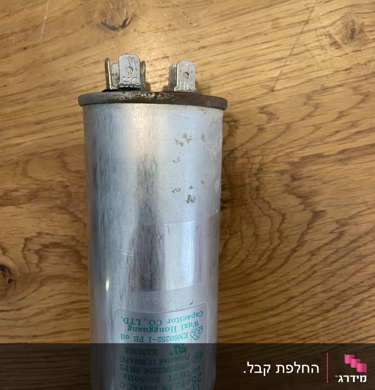 קבל מתכת עם חיבורים חשמליים על שולחן עץ